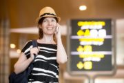 Woman making call in front of information board in airport